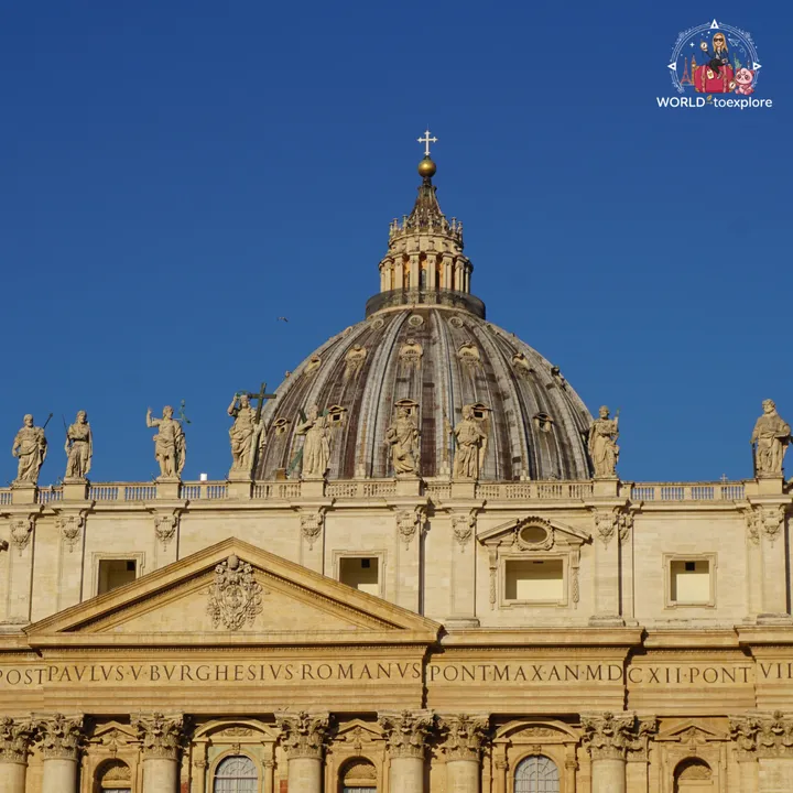 Michelangelo's dome rising behind the basilica façade, with the statues lined up along the balustrade and the Latin inscription