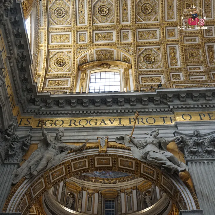 The gilded coffered ceiling of St Peter's Basilica, with the Latin inscription and two marble sculptures above an arch