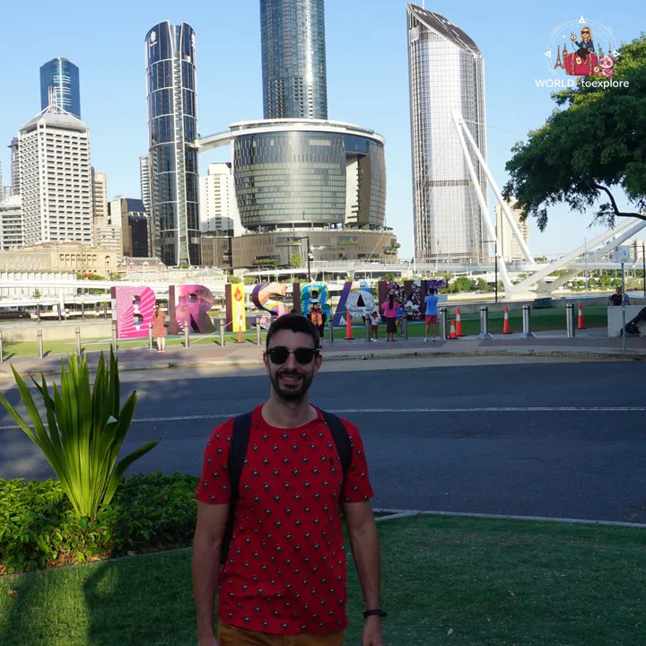 The colourful 'BRISBANE' sign by the river, with the city's skyscrapers in the background