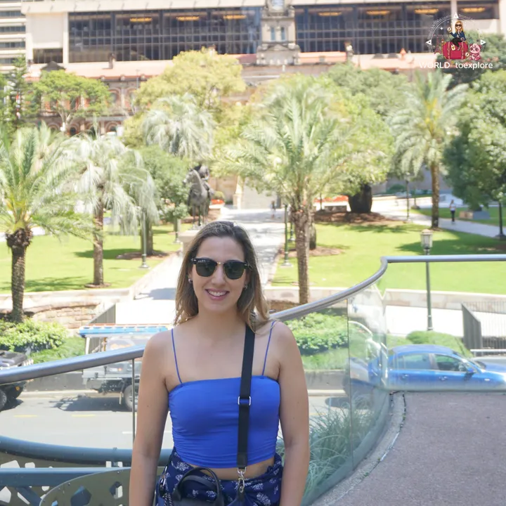 The gardens of Anzac Square, with palm trees and an equestrian statue, and a heritage building in the background