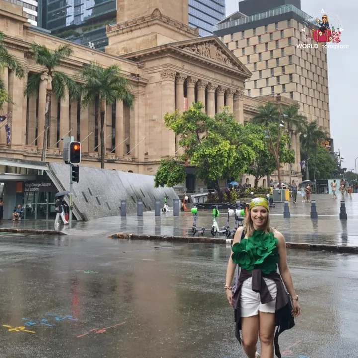 A heritage sandstone building with columns next to King George Square, on a rainy day