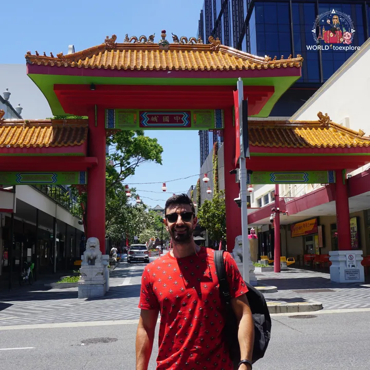 In front of the ceremonial Chinatown gate, decorated with red lanterns
