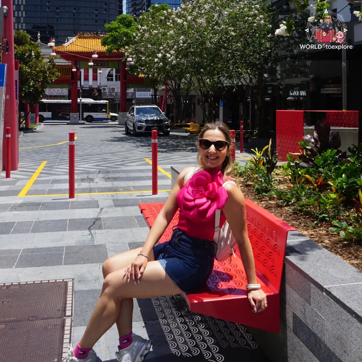 Sitting on a red bench at Chinatown Mall, with the Chinese gate in the background