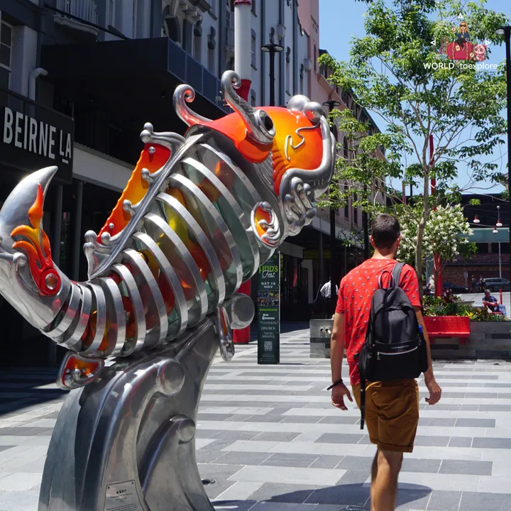 Walking past a large metal-and-glass carp sculpture in a Fortitude Valley laneway