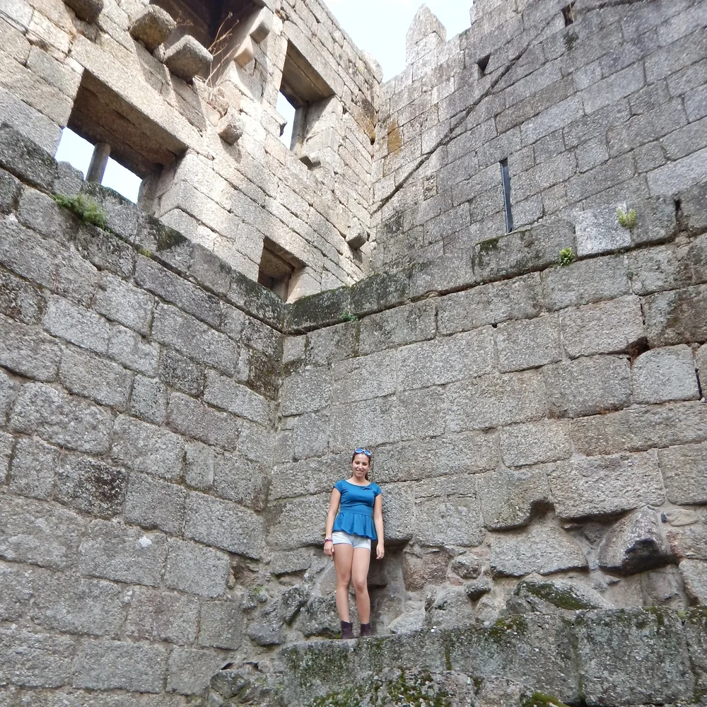 Woman in a blue top and shorts standing in the corner formed by two of the castle's towers