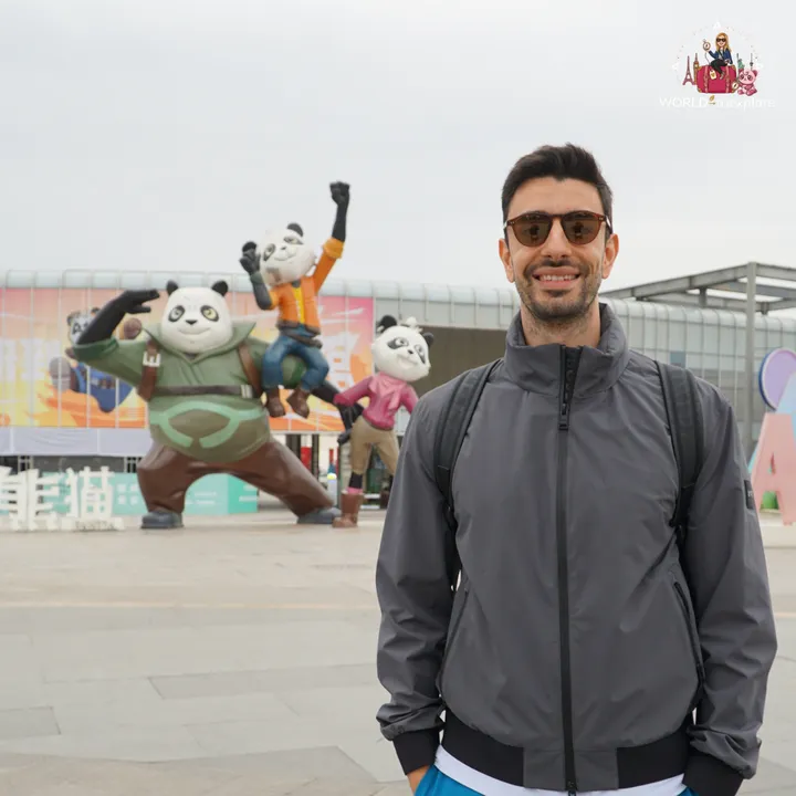 Man smiling next to the colourful Kung Fu Panda statues at the park entrance