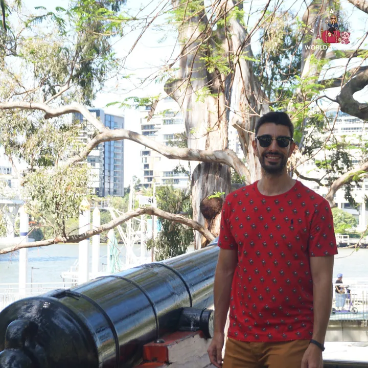 Next to an old historic cannon by the river, with buildings on the far bank