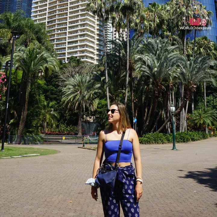 Among tall palm trees and a high-rise, in a paved square in the gardens