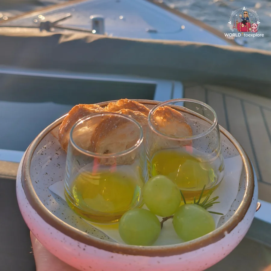 A plate with two glasses of olive oil, bread and green grapes for the olive oil tasting aboard the Sunset Cruise