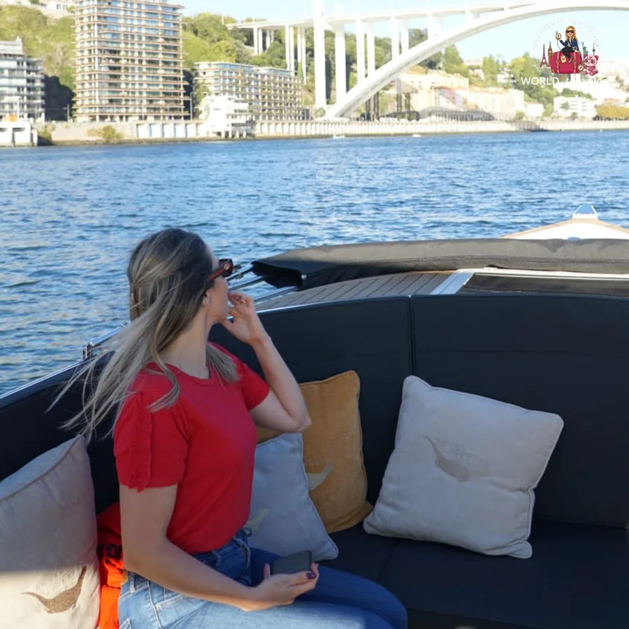 Cristina sitting sideways on the Wondy's seats, looking out over the River Douro with the Arrábida Bridge behind her