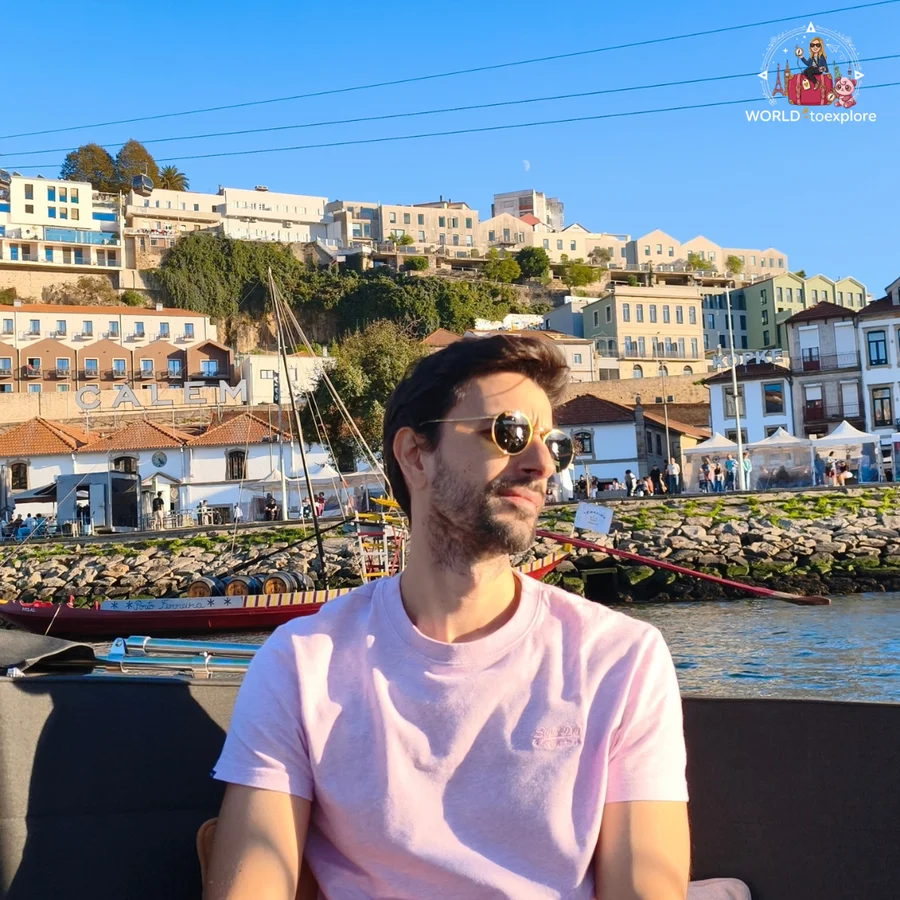 Her husband in sunglasses aboard the Wondy, with the Calém port wine cellars and a rabelo boat behind him in Vila Nova de Gaia