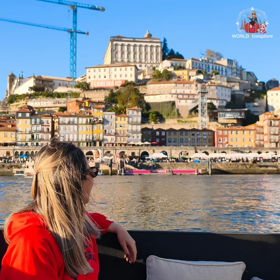 Cristina seen from behind, leaning on the Wondy's seat and looking at the Ribeira in Porto and the Episcopal Palace on top of the hill