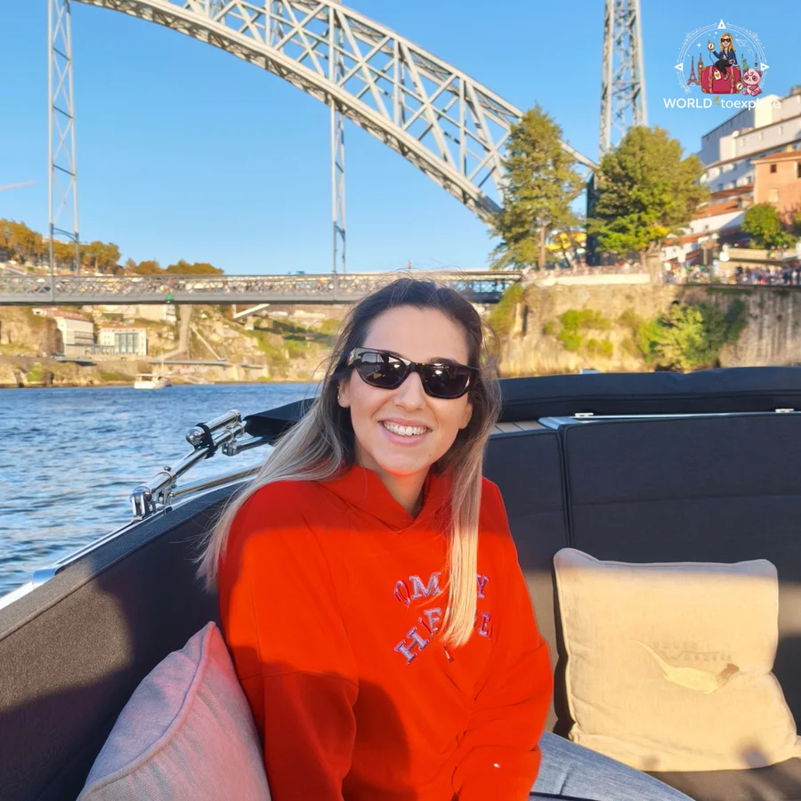 Cristina smiling aboard the Wondy, with the arch of the Luís I Bridge over the River Douro