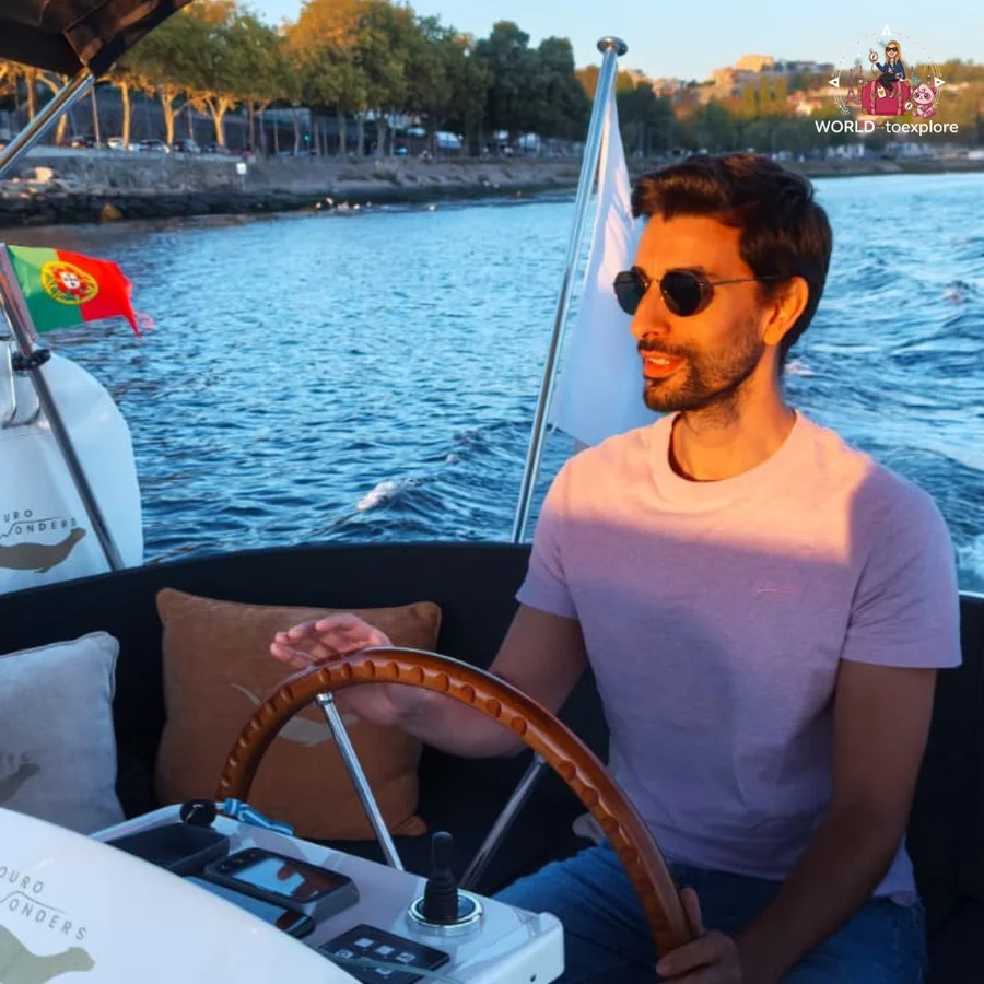 Her husband at the helm of the Wondy, with the Portuguese flag and the Douro Wonders name visible on the boat, and the riverbanks behind him