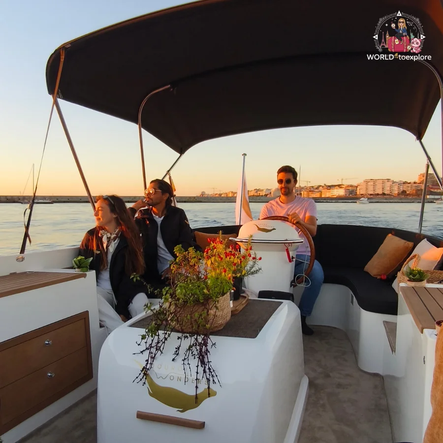 Passengers sitting on the Wondy looking out to sea in the late afternoon, with her husband at the helm under the canopy and the Porto coastline behind them