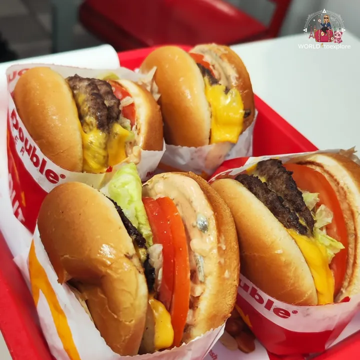 Four In-N-Out Double-Double burgers with cheese, lettuce and tomato, in a red tray
