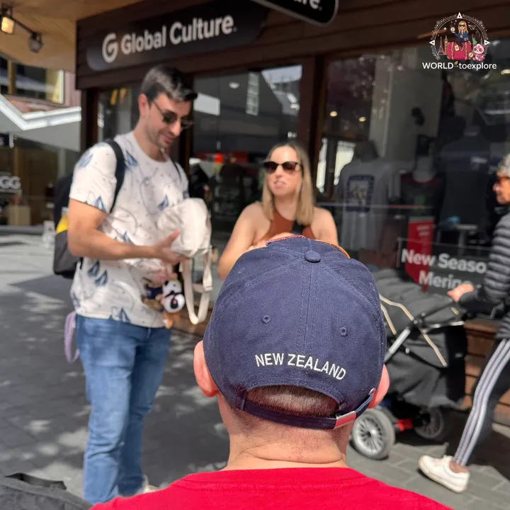 A group standing by the window of the Global Culture shop in Queenstown, with a cap reading New Zealand in the foreground