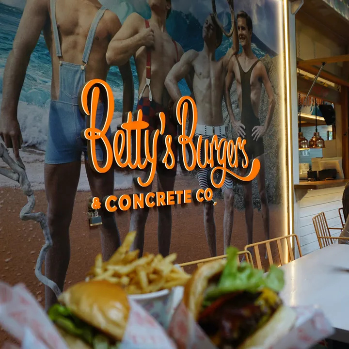 The orange Betty's Burgers & Concrete Co. sign, with a burger and fries out of focus in the foreground