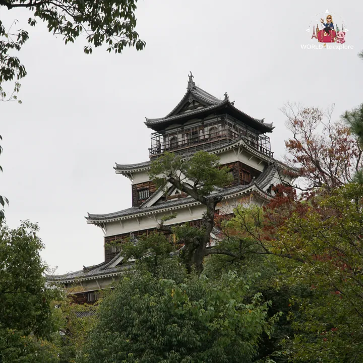 Close-up of the main keep of Hiroshima Castle, with its dark upper floors, among the trees