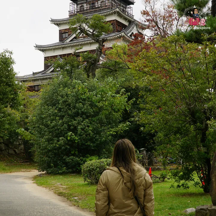 The main keep of Hiroshima Castle seen from a garden path, surrounded by greenery
