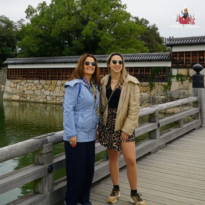 On a wooden bridge over the moat of Hiroshima Castle, with the stone walls behind