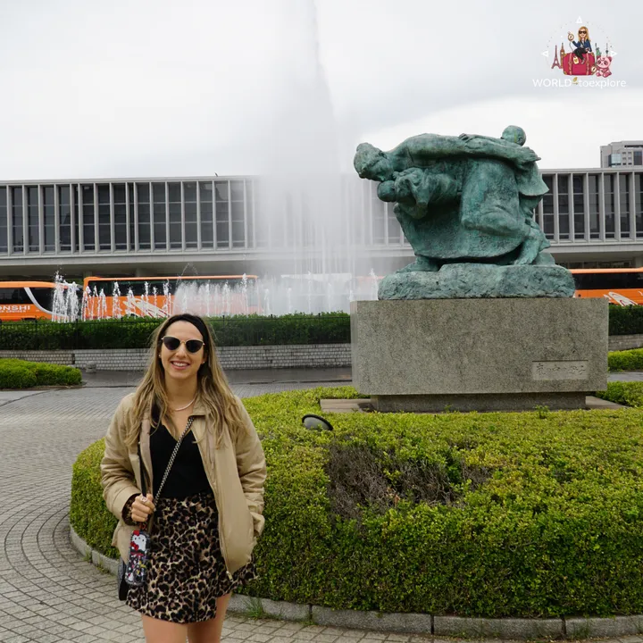 By the Fountain of Prayer, with a bronze sculpture of embracing figures on a granite pedestal and the museum building behind