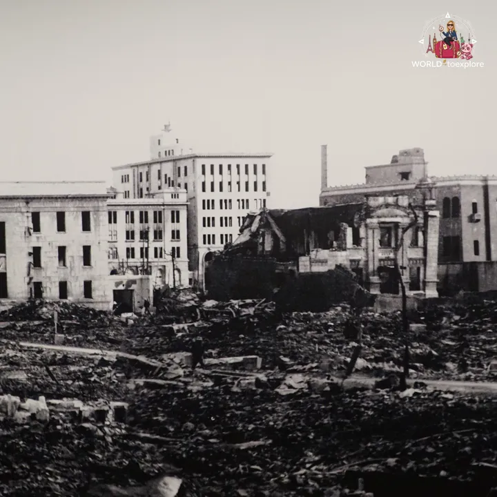 Black and white photograph of Hiroshima in ruins, with rubble in the foreground and destroyed buildings behind