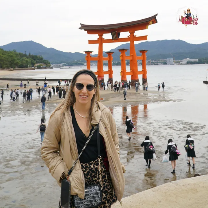 In front of the great torii at low tide, with a group of uniformed students strolling across the wet sand