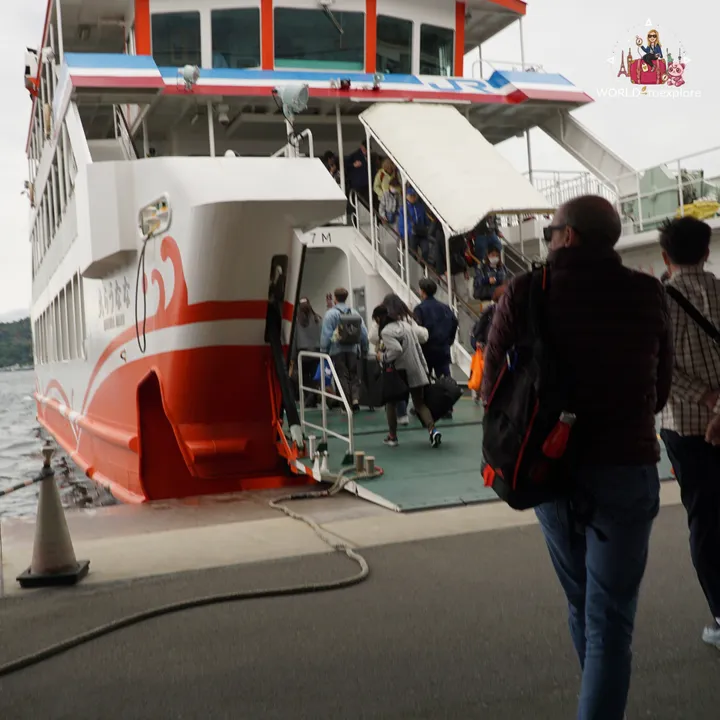 The JR ferry moored at the pier, with passengers boarding up the covered ramp on their way to Miyajima