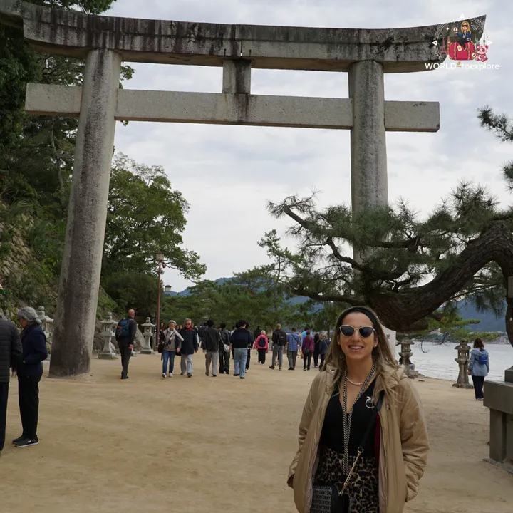 Beside the stone torii at the start of the path to the shrine, lined with pine trees and stone lanterns