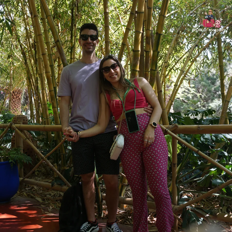 Couple embracing in front of a clump of bamboo, he in a lilac T-shirt and she in a pink top