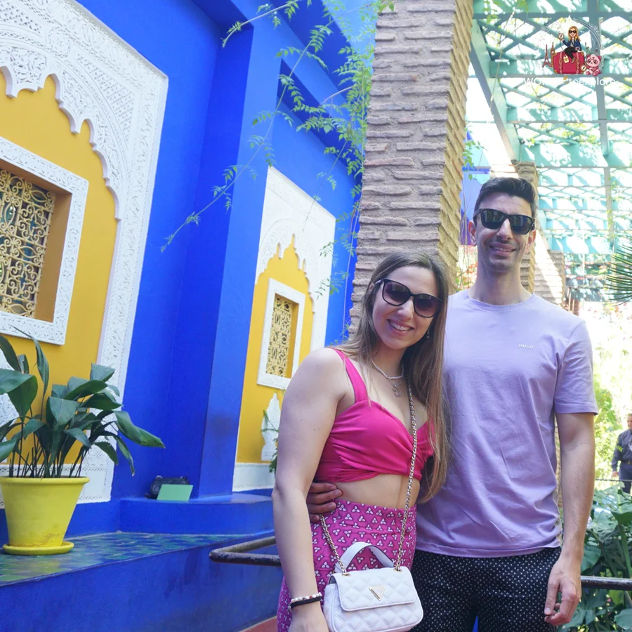 Smiling couple in front of a blue and yellow wall with a decorative white stucco cut-out