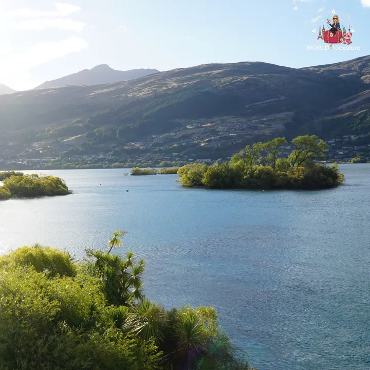 Panoramic view of Lake Wakatipu with tree-covered islets and the Queenstown mountains in the background