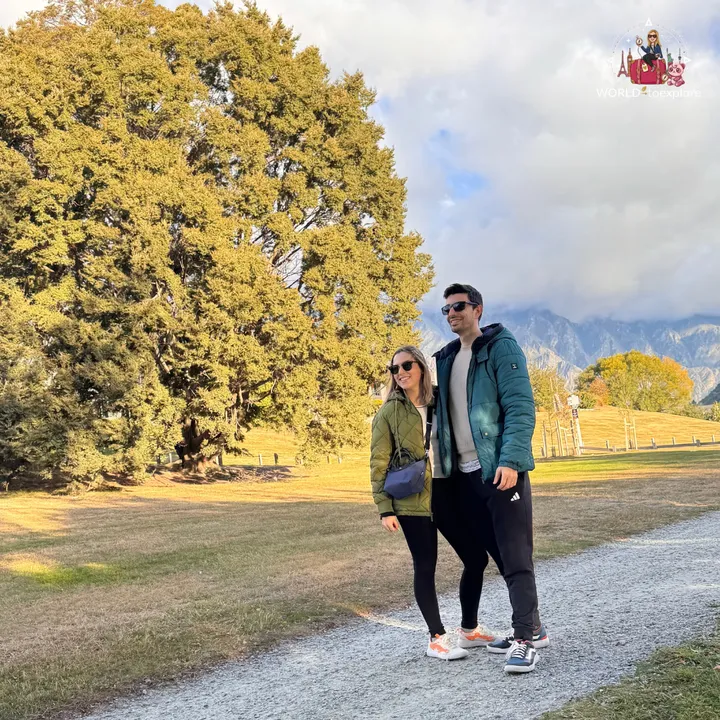 A couple smiling next to a tree with yellow autumn leaves, in the Peace Park Wakatipu Reforestation Trust