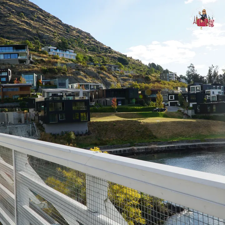 Modern houses built on the hillside next to Lake Wakatipu, seen from the dam bridge