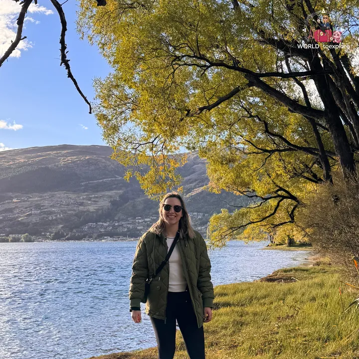 The author smiling under a tree with yellow autumn leaves, by Lake Wakatipu