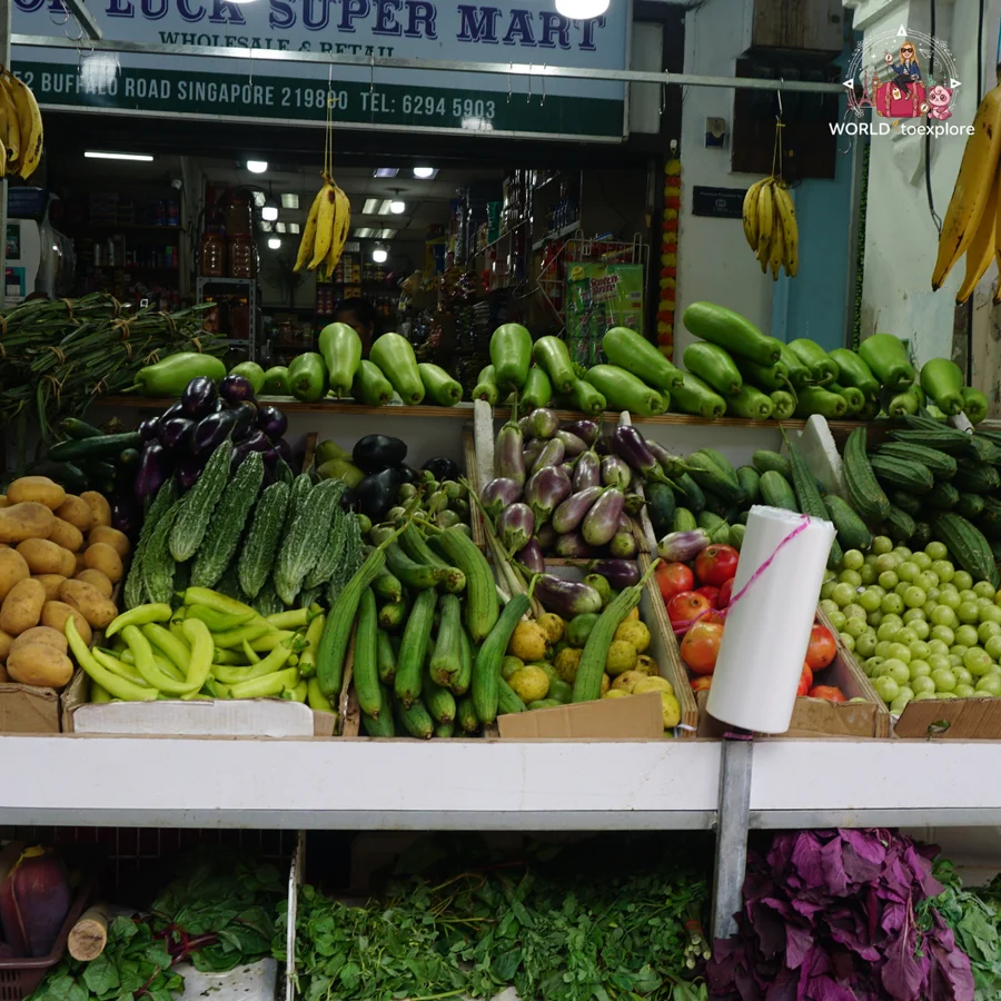 A vegetable and fruit stall outside a grocery shop in Little India, with courgettes, aubergines and bananas