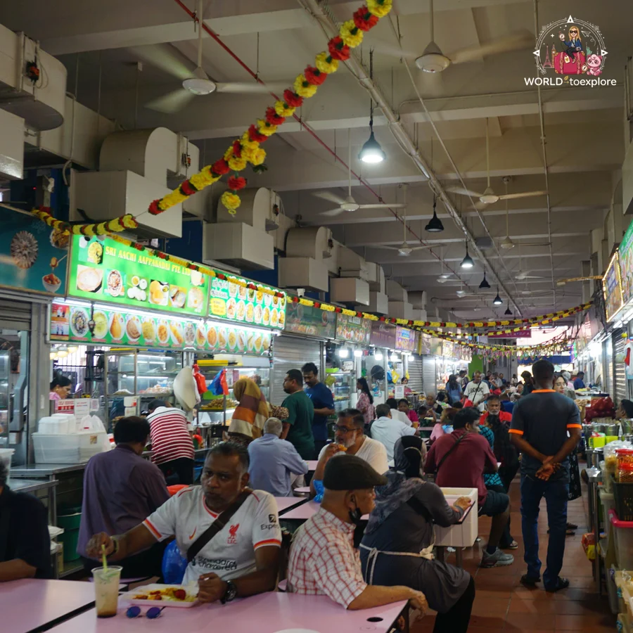 A busy food court, decorated with yellow and red garlands, in a market in Little India