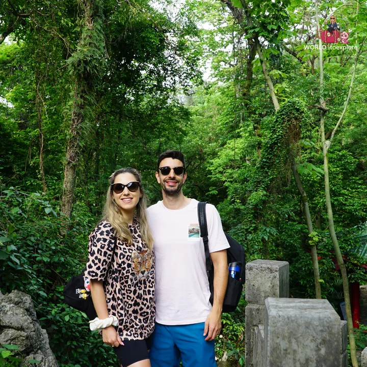Couple smiling next to a stone gate, surrounded by trees, on Diecai Hill