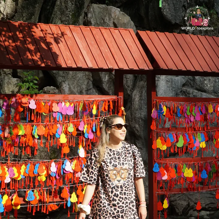 Cristina smiling next to panels with colourful gourd charms hanging, inside Wind Cave