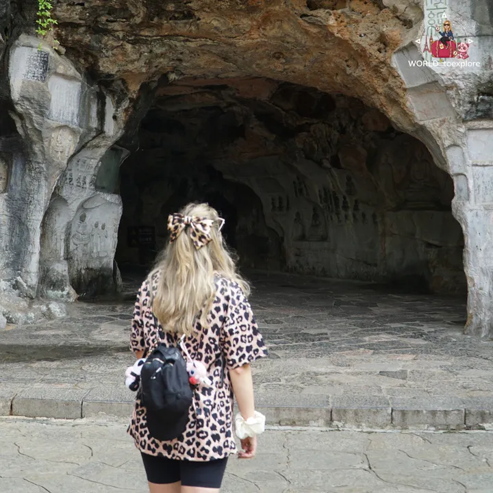 Cristina from behind, looking into Wind Cave, with Buddha carvings on the rock
