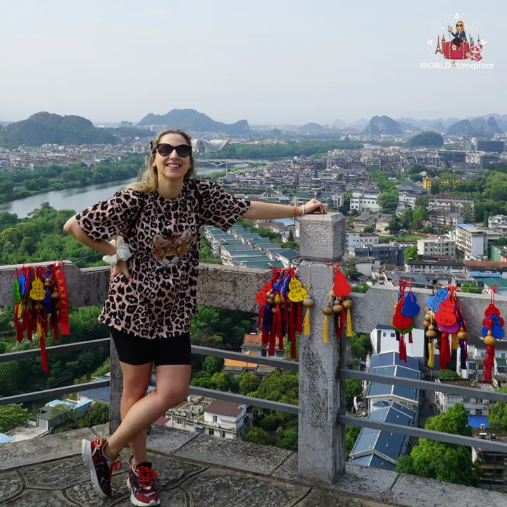 Cristina smiling at the top of Diecai Hill, with the city of Guilin and karst mountains in the background