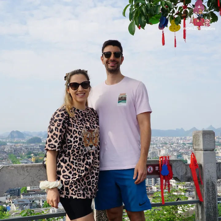 Couple smiling at the top of Diecai Hill, with the city of Guilin in the background