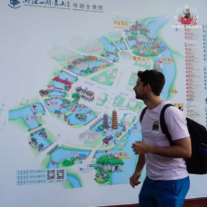 Man walking past the map board for the Two Rivers and Four Lakes complex, including Diecai Hill