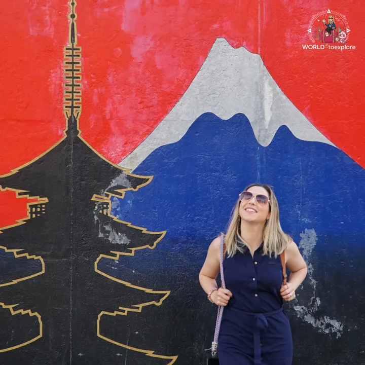 Standing in front of an East Side Gallery mural with Mount Fuji and a pagoda painted on a red background