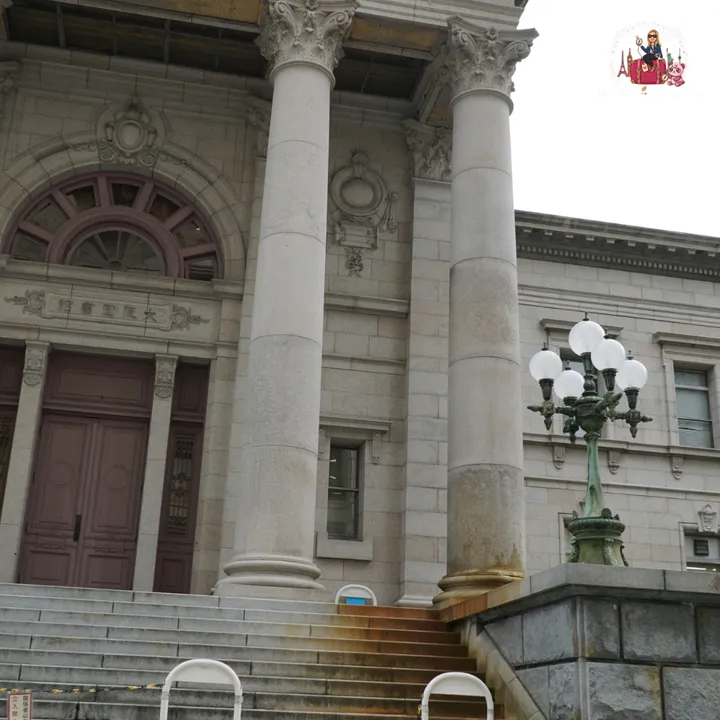 Stone entrance with Corinthian columns of a neoclassical building in Nakanoshima, with an old lamp post beside it
