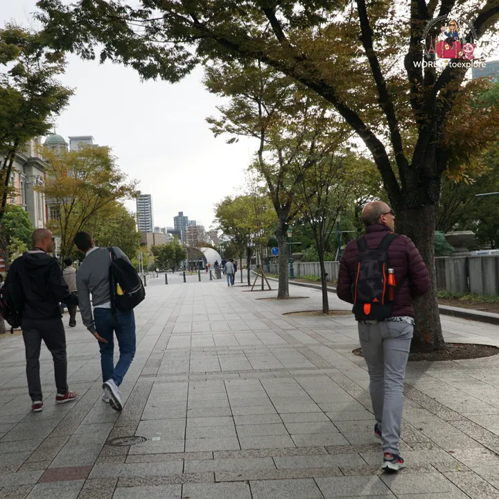 Group of three men walking along a tree-lined path in Nakanoshima