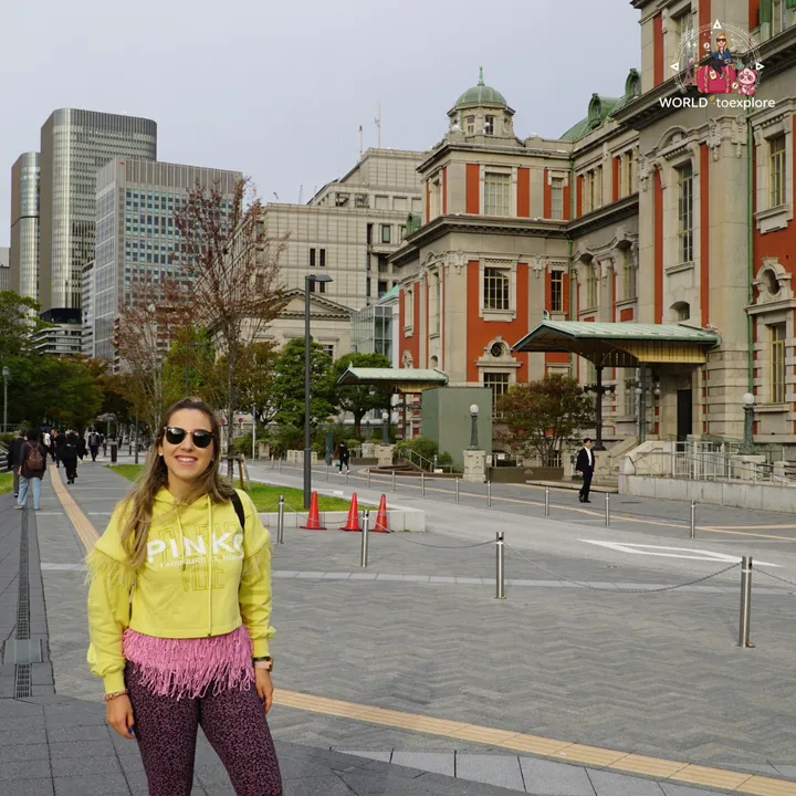 Smiling woman in front of Osaka City Central Public Hall, with its red-brick façade in the background
