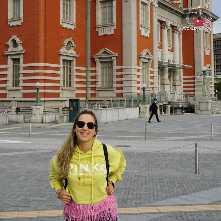 Smiling woman in front of Osaka City Central Public Hall, with the columns and red-brick façade in close-up