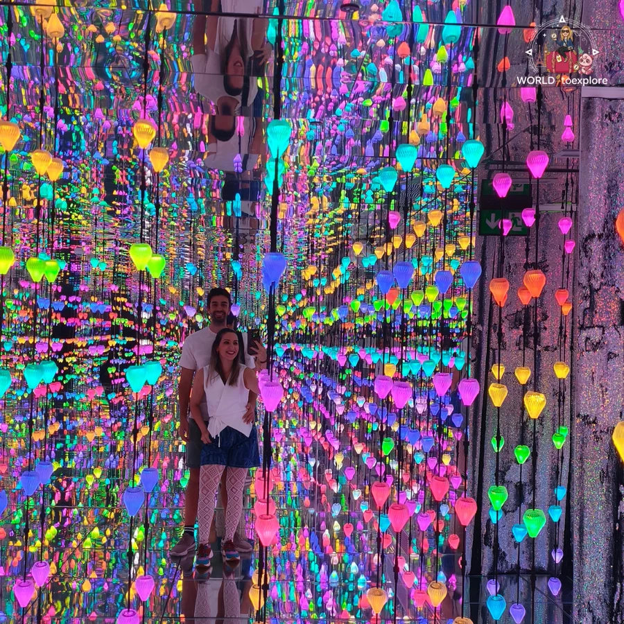 Cristina and her husband reflected in a mirror room with thousands of coloured lights, at Neonia in Porto